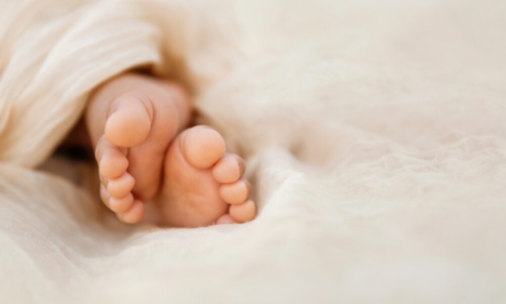 Newborn baby feet closeup on soft cream wrap in a selective focus