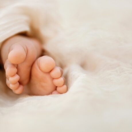 Newborn baby feet closeup on soft cream wrap in a selective focus