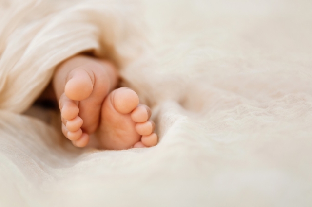 Newborn baby feet closeup on soft cream wrap in a selective focus