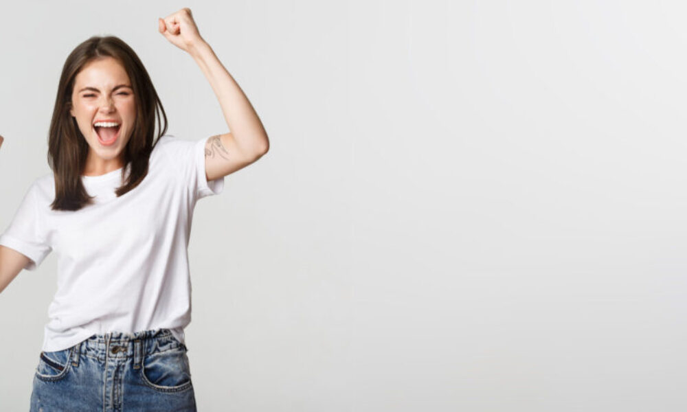 Cheerful attractive brunette girl fist pump and smiling with rejoice, winning
