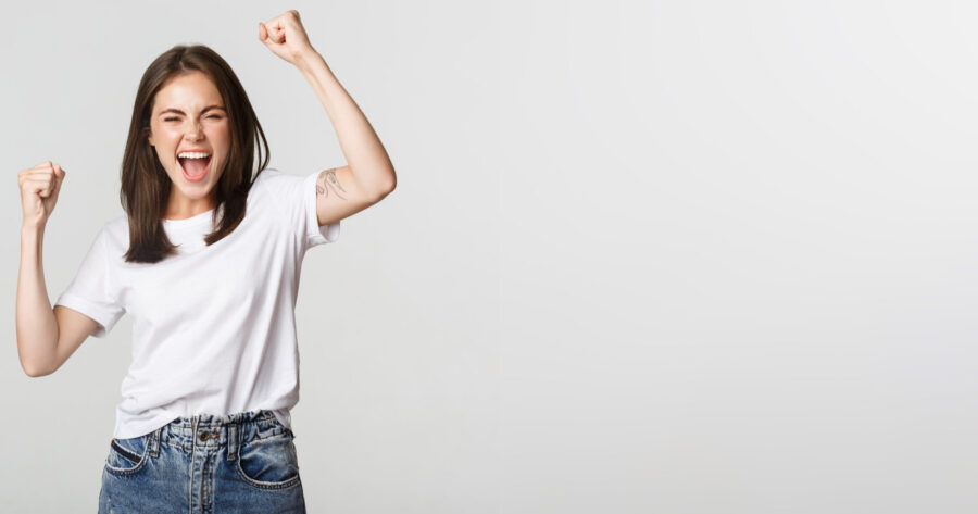 Cheerful attractive brunette girl fist pump and smiling with rejoice, winning