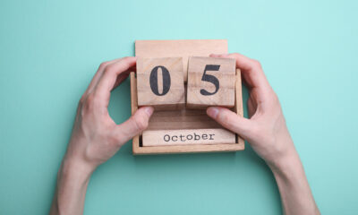 Hand holding wooden block calendar with date october 05 on mint green background
