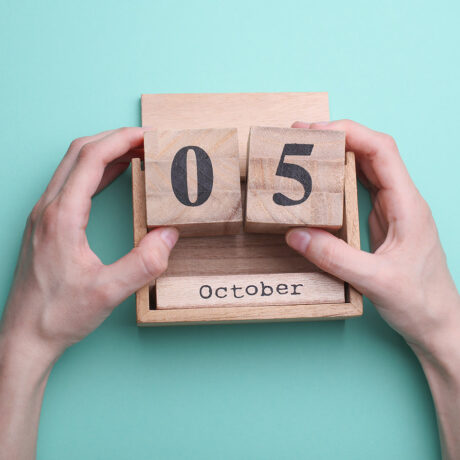 Hand holding wooden block calendar with date october 05 on mint green background