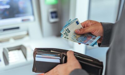 A,Person,Accessing,An,Atm,And,Holding,Euro,Currency,Notes