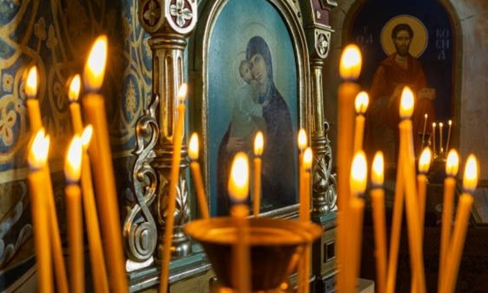 Blurred wax burning candles in an orthodox church on the icon background.