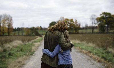 Mother and daughter hugging on dirt road, Lakefield, Ontario, Canada